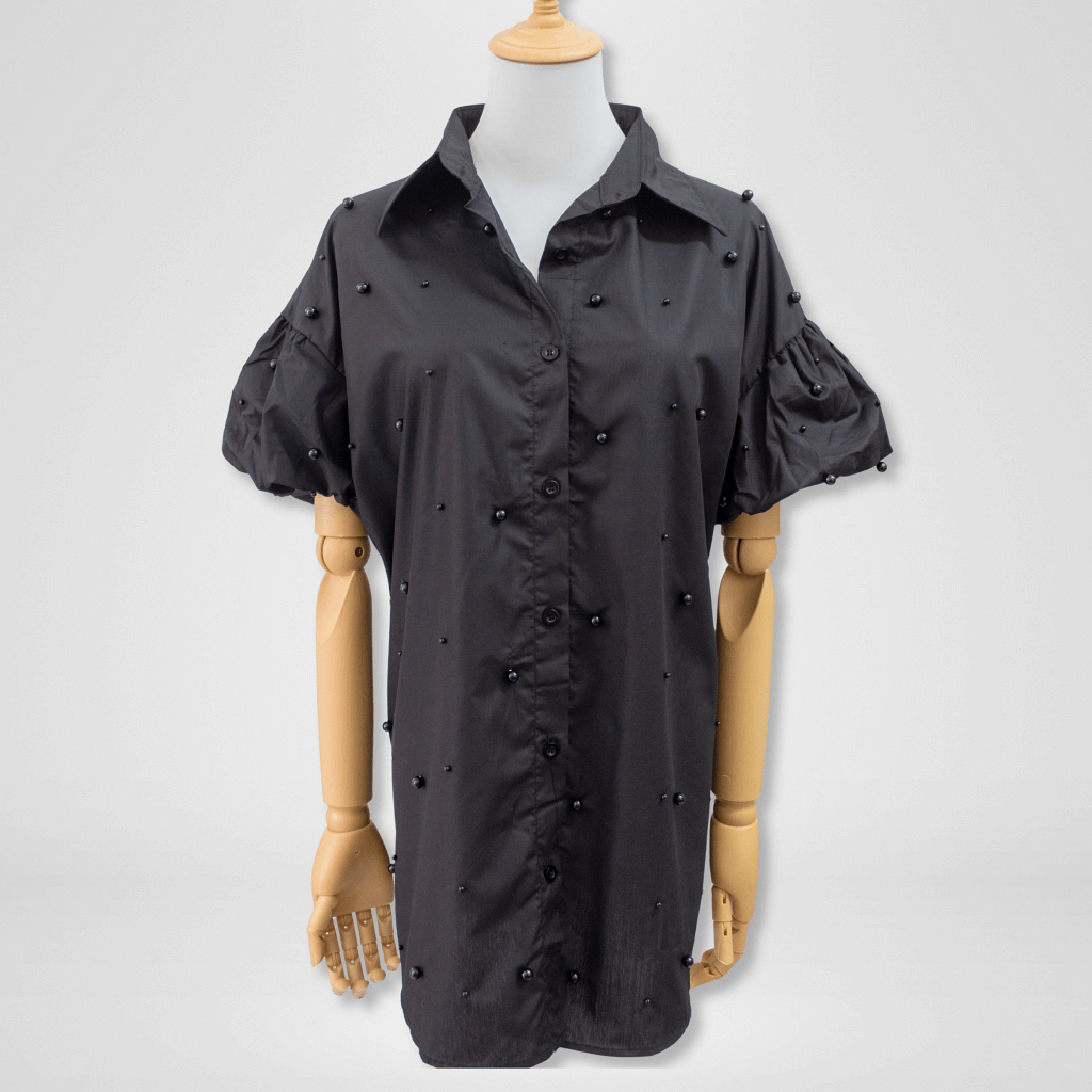 Black shirt with pearl embellishments on a mannequin against a white background