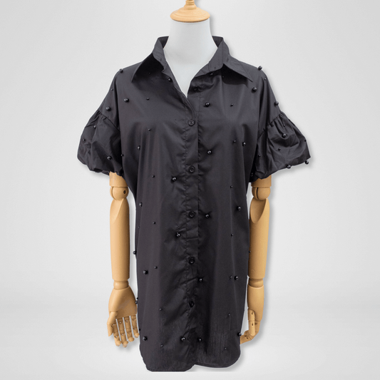 Black shirt with pearl embellishments on a mannequin against a white background