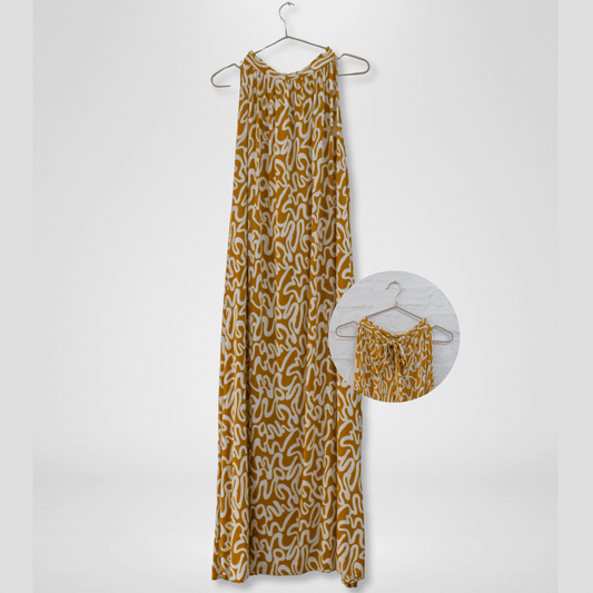 Long mustard yellow dress with white pattern on a hanger against a white background